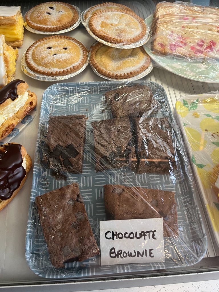 Chocolate brownies, eclairs and fruit tarts in the display case